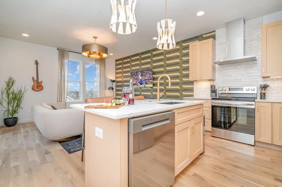 A vibrant, welcoming kitchen area featuring a large kitchen island, a decorative wall, modern lighting fixtures, and a guitar mounted on the wall. This open space is ideal for gathering, dropping off groceries or bags, and getting settled in.
