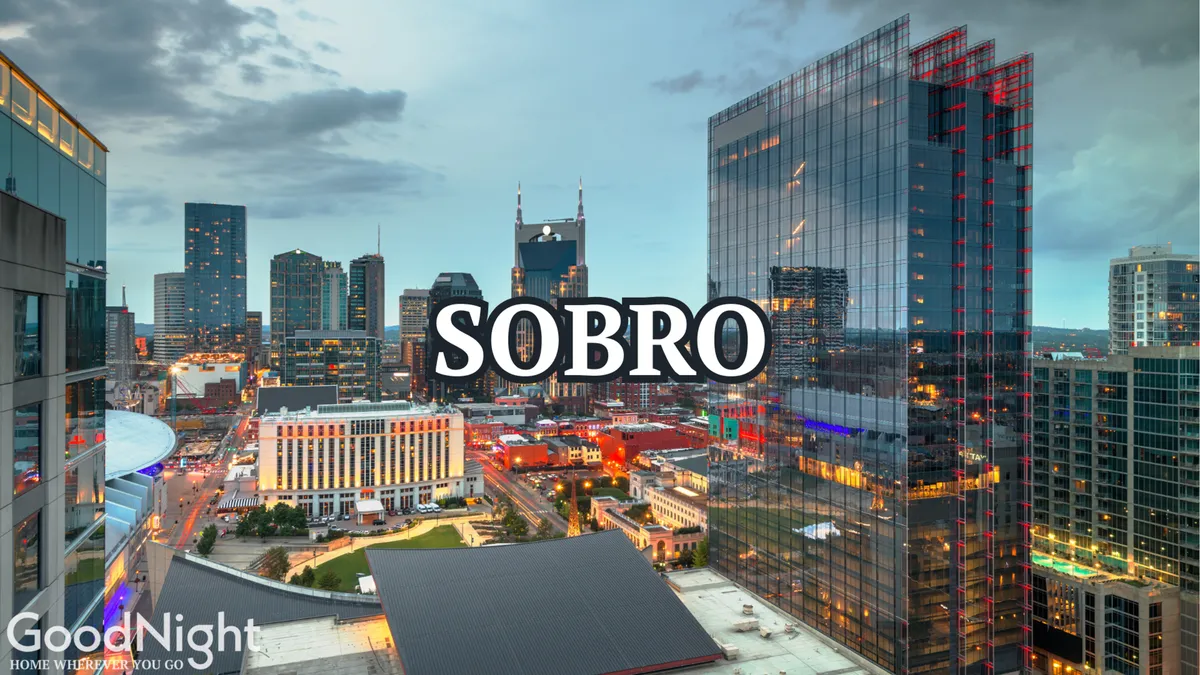 This view features Nashville’s illuminated skyline with the SOBRO sign and modern architecture. The city lights create an energetic atmosphere, hinting at the vibrant urban experience available from the rooftop setting.