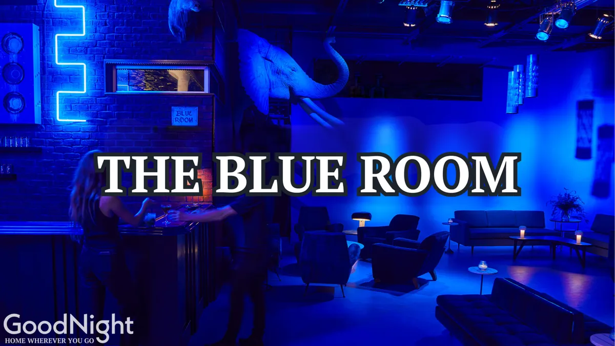 An atmospheric interior/exterior bar scene illuminated by neon signs and blue lighting, featuring a stylish bar, lounge seating, and eye-catching wall art. The ambiance is upscale and social, ideal for group gatherings and celebrations.